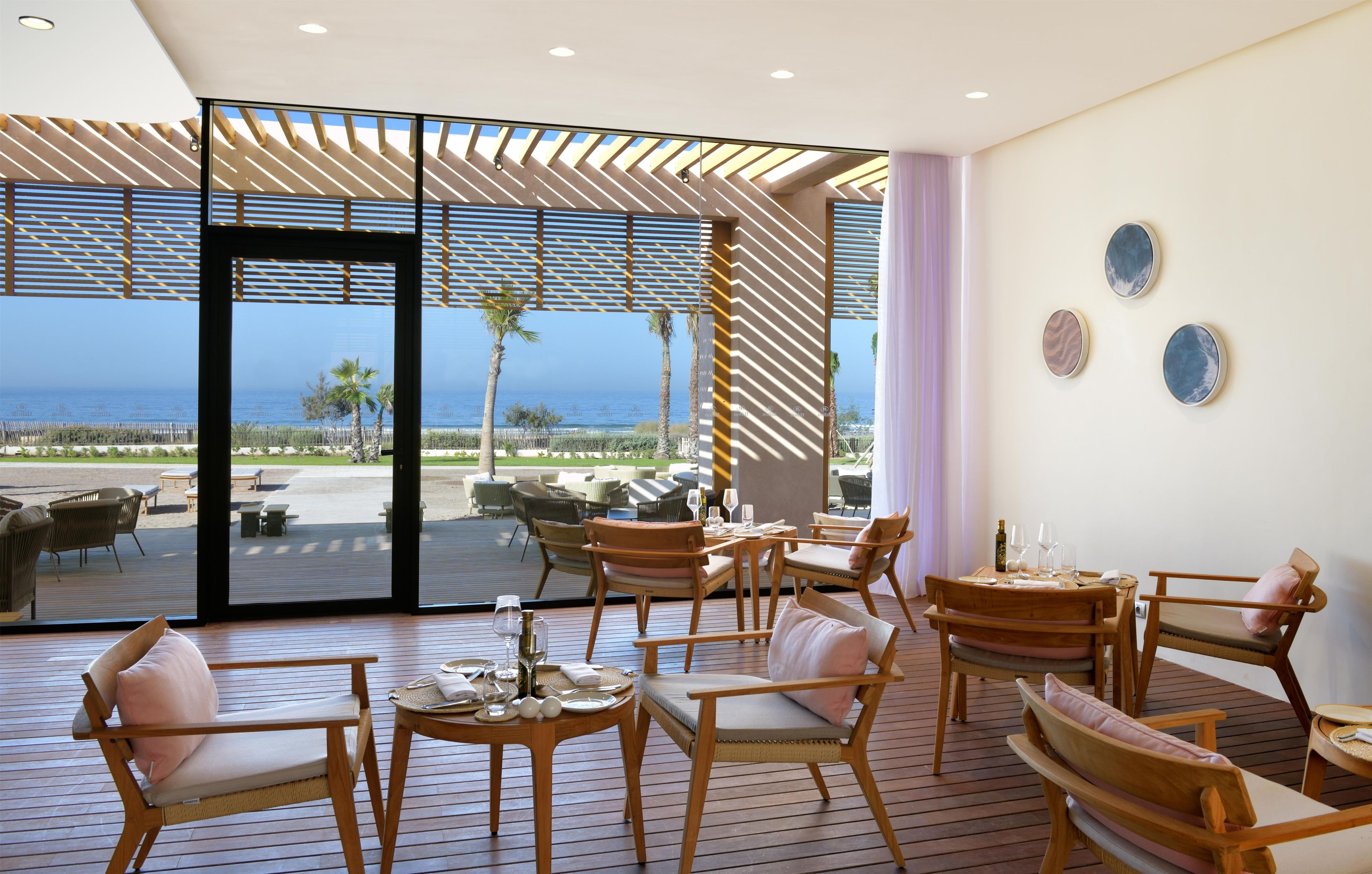 Un área de estar moderna al aire libre con muebles de madera y vista al mar.