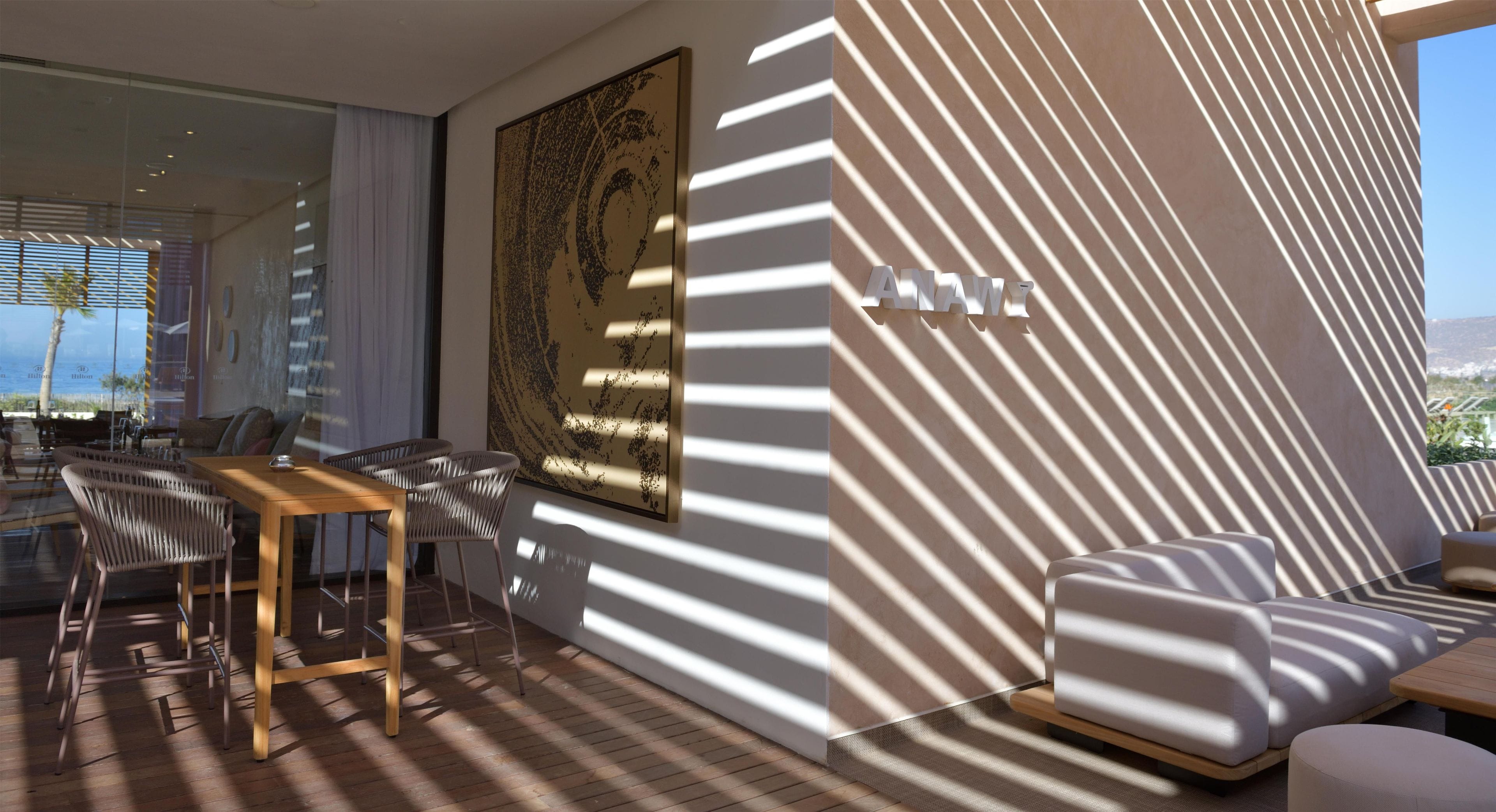 A modern interior with a dining area, a large abstract artwork, and a seating area with a view.