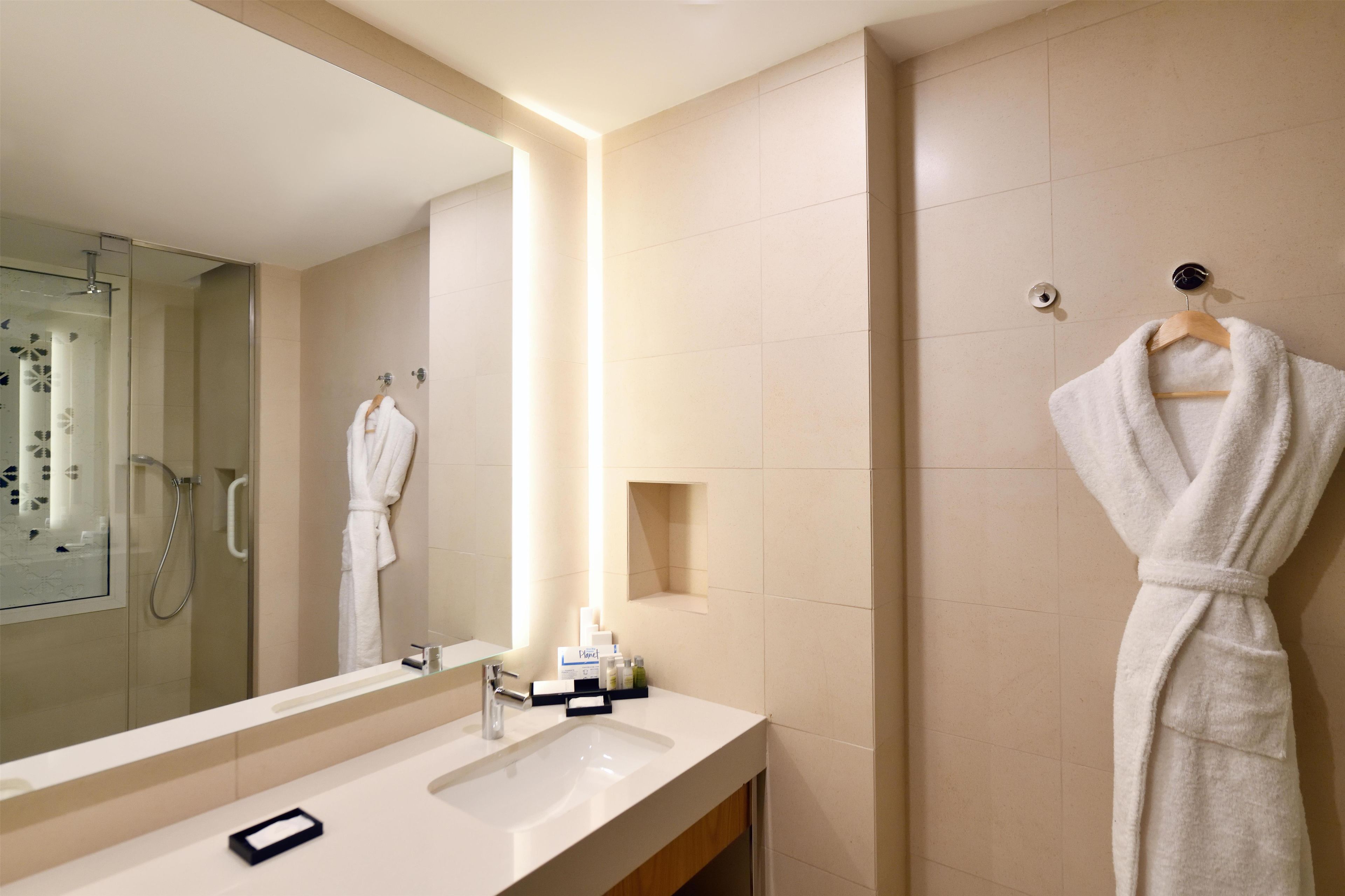 Une salle de bain moderne avec un grand miroir, une douche et un meuble-lavabo avec un évier.