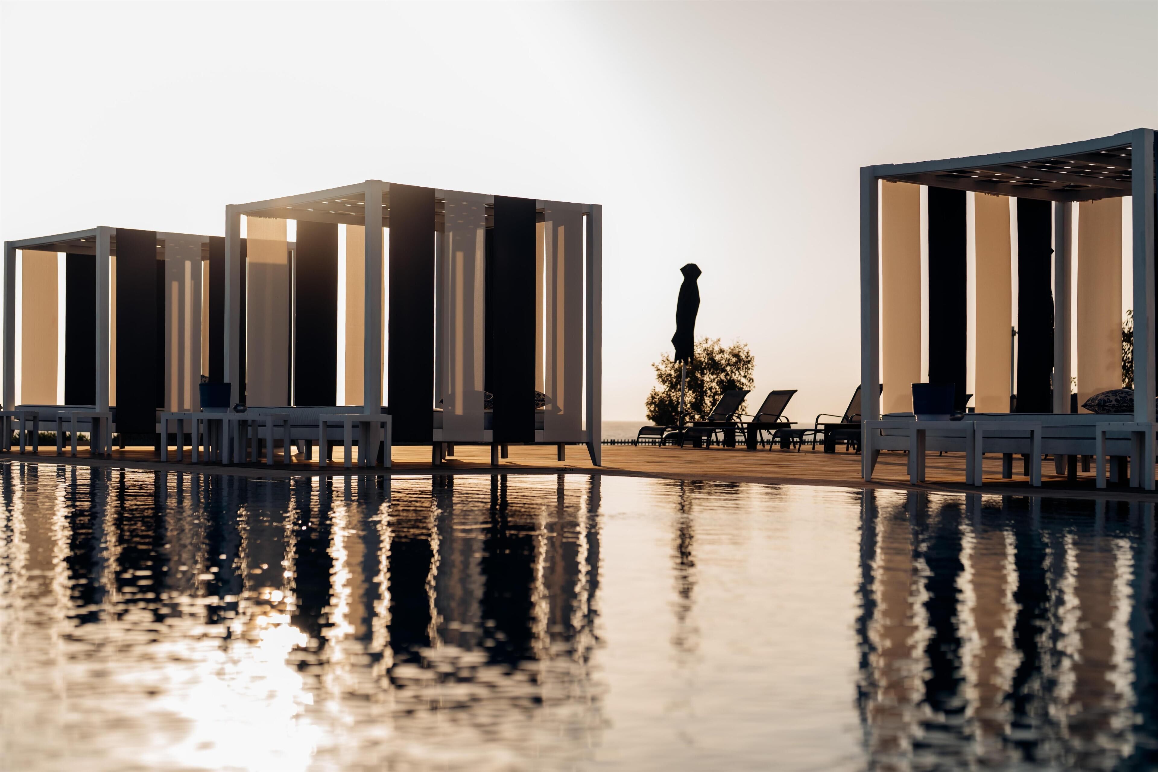 A poolside area with lounge chairs and a statue.