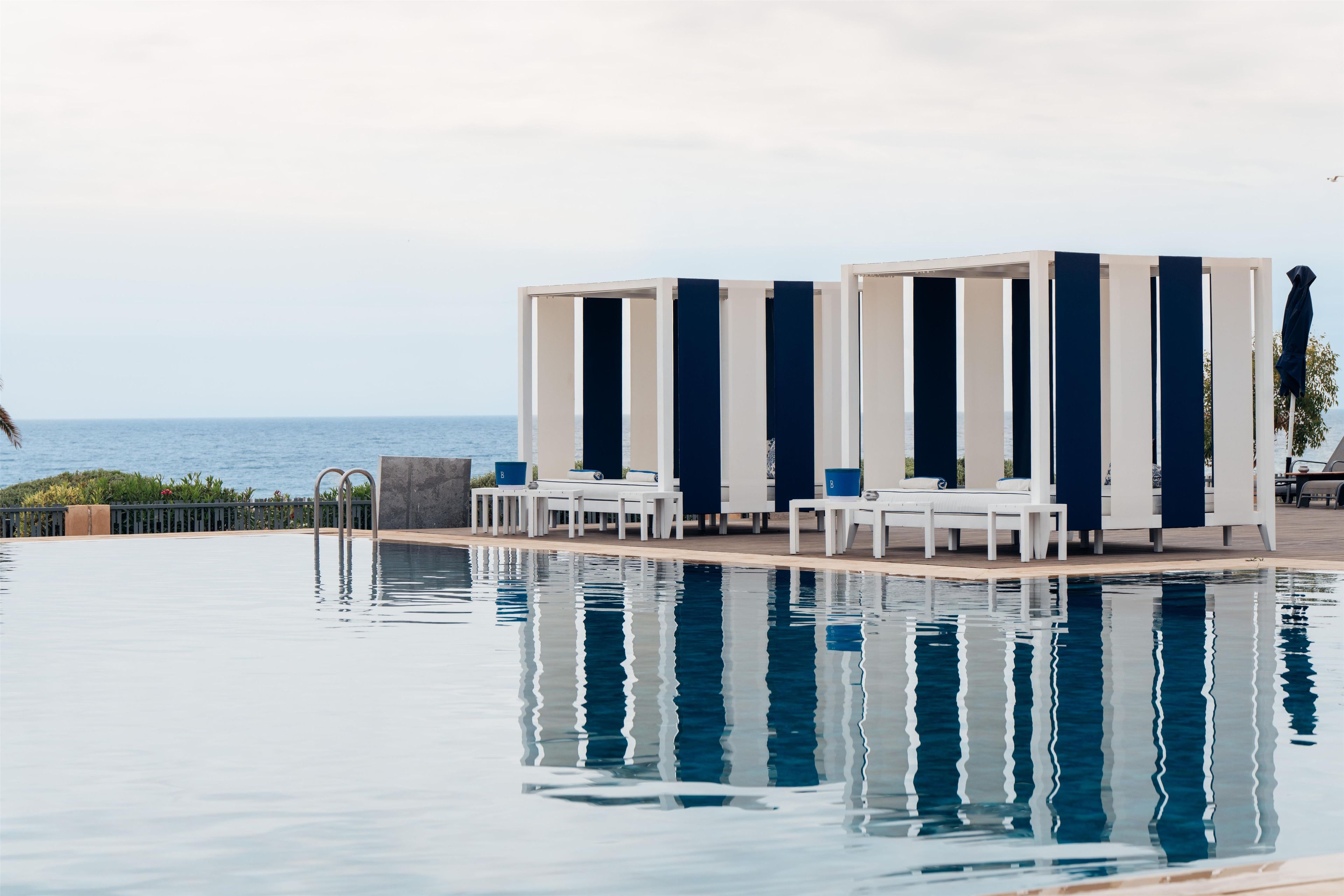 A swimming pool with lounge chairs and a view of the sea.