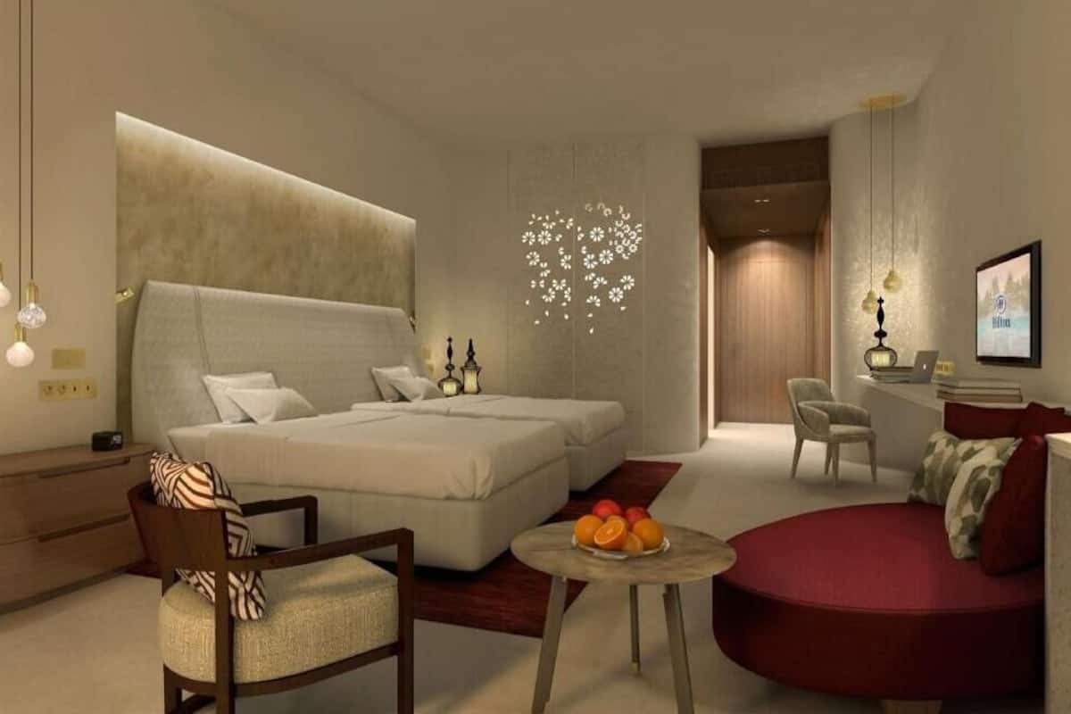 Een moderne hotelkamer met een groot bed, een zithoek en een klein tafeltje met fruit.