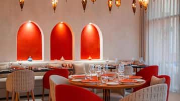 Ein Restaurant mit runden Tischen, roten Stühlen und hängenden Lampen.