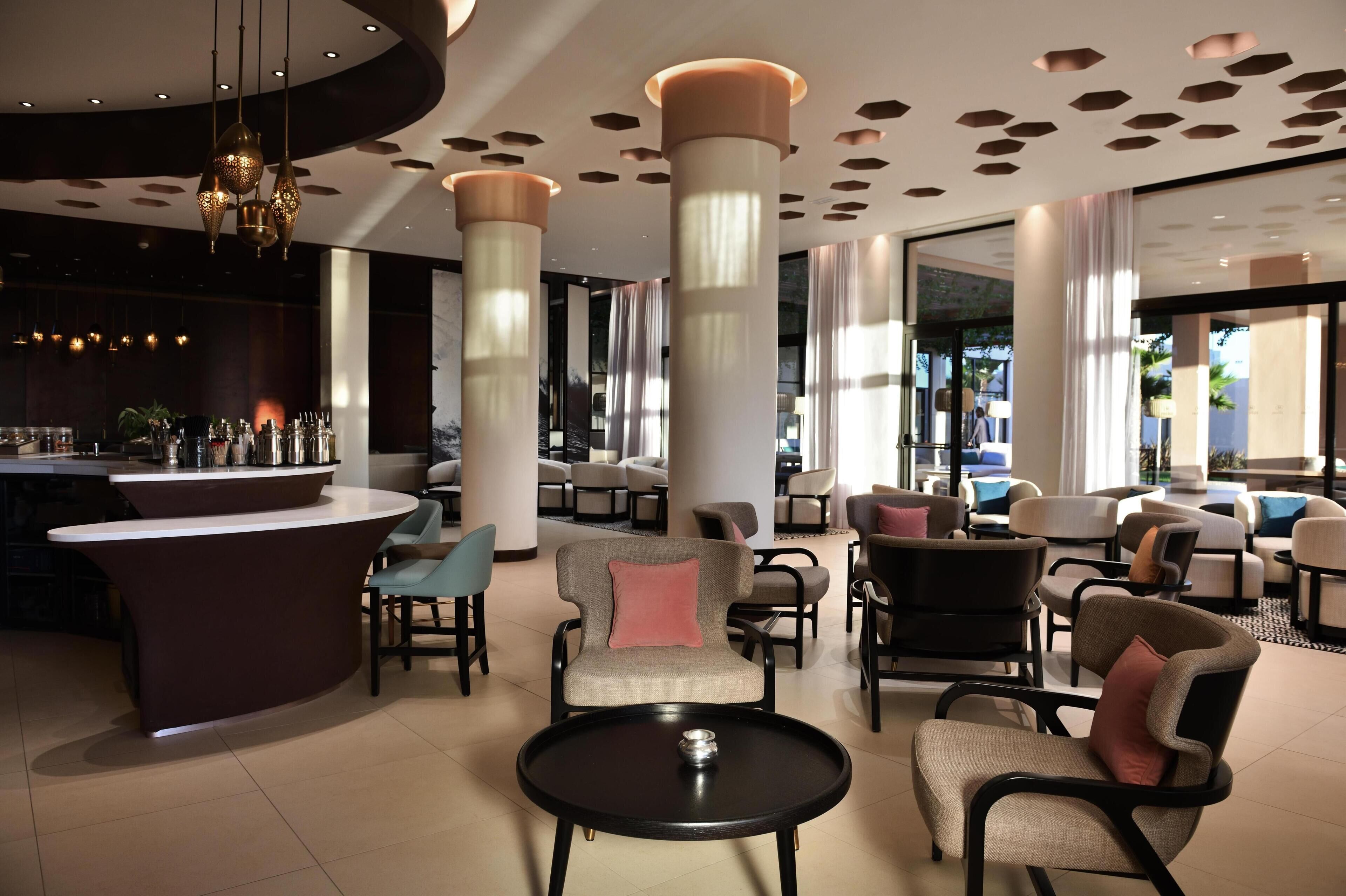 Un espace de détente moderne doté d’un bar, de différents types de sièges et de grandes colonnes.