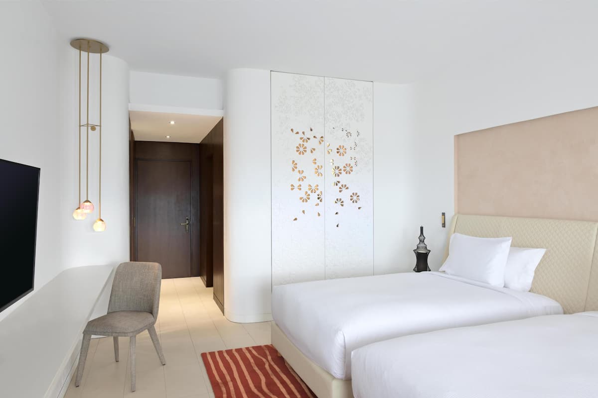 Een hotelkamer met een bed, een stoel, een televisie en een decoratief wandpaneel.
