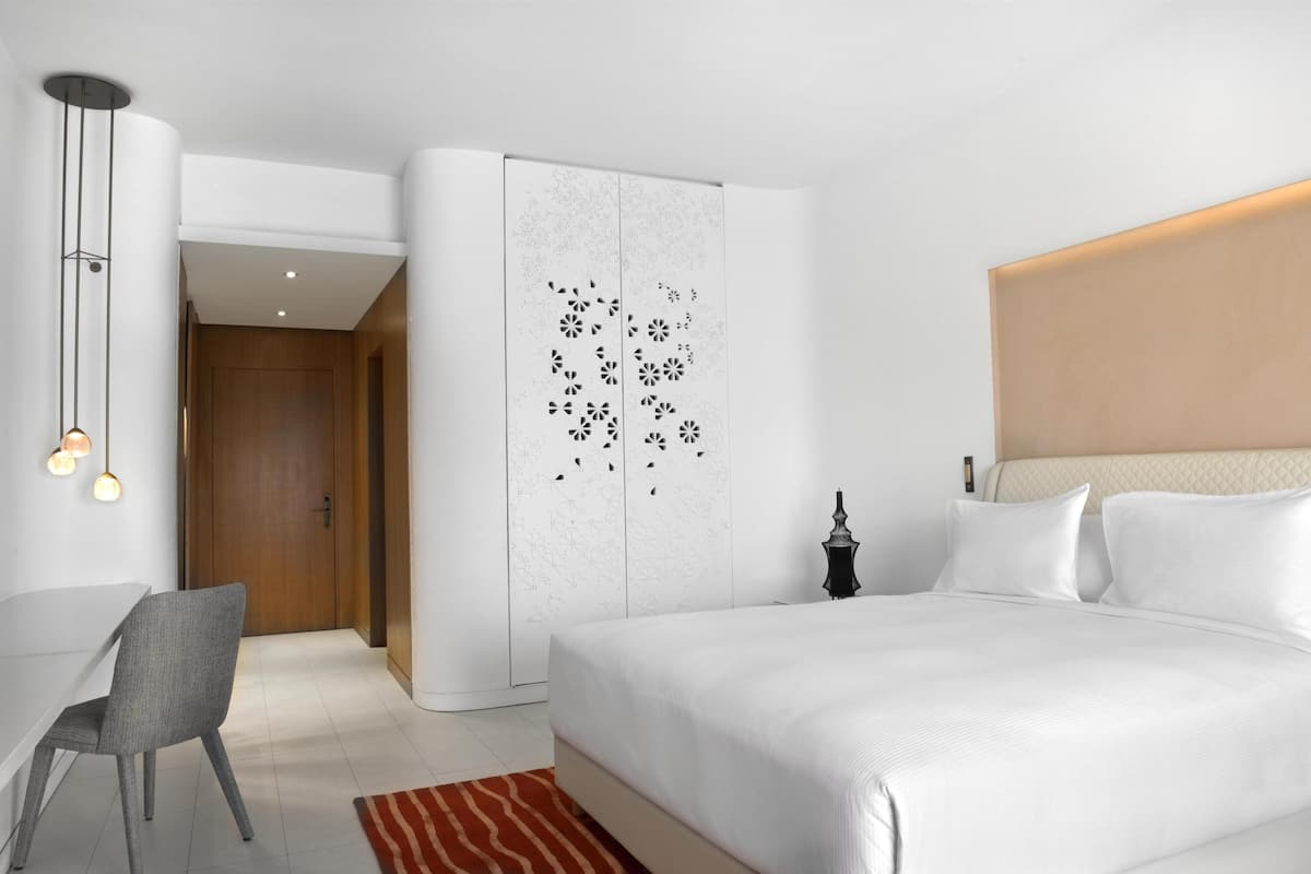 Een moderne hotelkamer met een groot bed, een bureau en een kledingkast.