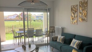 Un salon moderne avec un canapé vert, un fauteuil jaune et un coin repas comprenant une table et des chaises.
