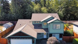 A two-story house with a garage, a covered porch, and a fenced backyard. - Spotless Modern Spacious 1 min to Hurricane Ridge entrance Patio Family friendly (Port Angeles)