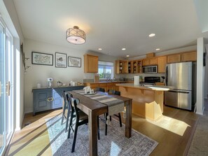 Una cocina moderna con armarios de madera, electrodomésticos de acero inoxidable y una zona de comedor con una mesa y sillas.