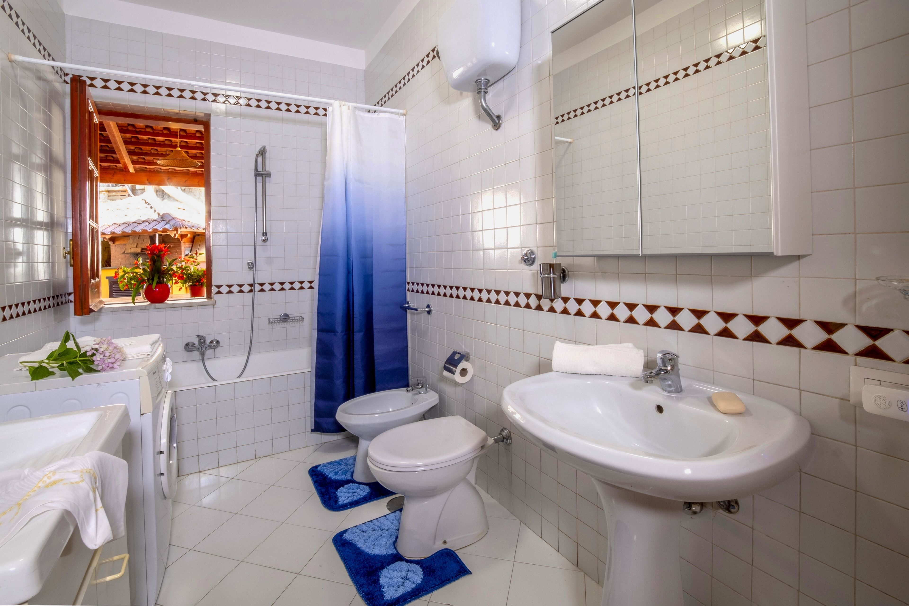 Un baño con lavadora, bidé, inodoro, lavamanos y ducha.