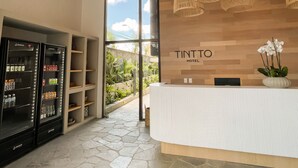 Zona de recepción de un hotel con un mostrador de madera, un minibar y vistas al exterior.