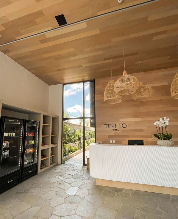 Zona de recepción de un hotel con un mostrador de madera, un minibar y vistas al exterior.