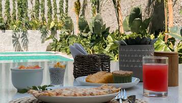 A table with a plate of food, a glass of red drink, and a woven placemat.