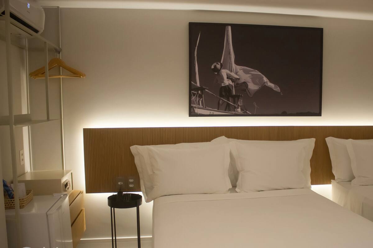 A hotel room with a bed, a nightstand, a lamp, and a wall-mounted painting.