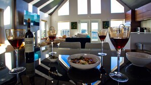 A dining table with wine glasses, a bottle of wine, and a bowl of salad. - Au Bon Orchard - Catskills Mountain Views/Private Heated Pool and Jacuzzi (Parksville)
