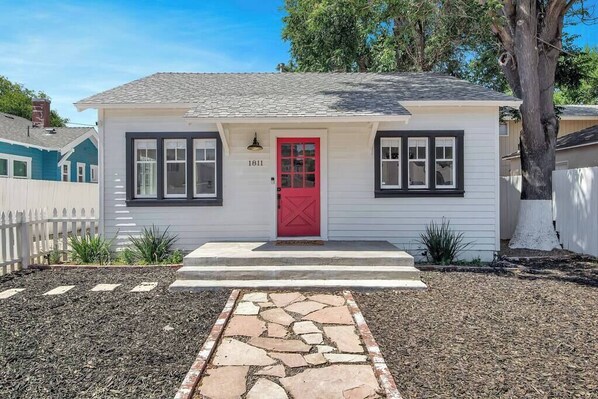 A single-story house with a red door, numbered 1811, and a stone pathway leading to the entrance.