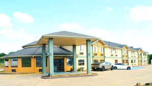 A motel with a covered front area, multiple windows, and a parking lot with cars. - Sonesta Essential Van Buren Fort Smith (Van Buren)