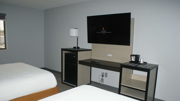 A hotel room with two beds, a desk with a television, a lamp, and a coffee maker. - Sonesta Essential Van Buren Fort Smith (Van Buren)