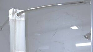 A shower with a white curtain and marble tiles. - Sonesta Essential Van Buren Fort Smith (Van Buren)