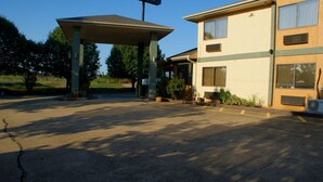 A building with a covered parking area, a small garden, and a large window on the side. - Sonesta Essential Van Buren Fort Smith (Van Buren)