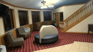 A spacious living area with a large sofa, two armchairs, a ceiling fan, and a staircase. - Sonesta Essential Van Buren Fort Smith (Van Buren)