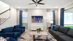 Ein modernes Wohnzimmer mit Stadtbildgemälde, zwei Sofas, einem Couchtisch und einem Deckenventilator.