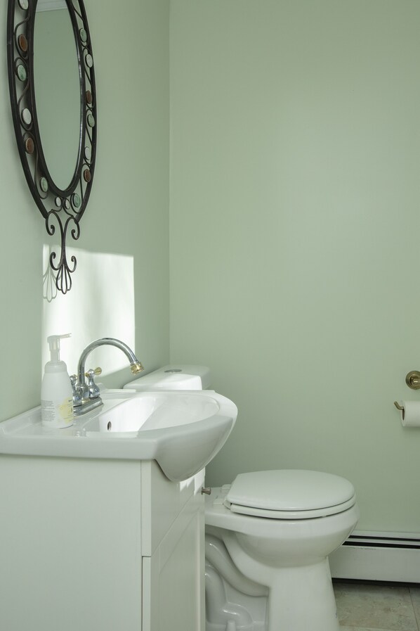 A bathroom with a white sink, a toilet, and a decorative mirror.