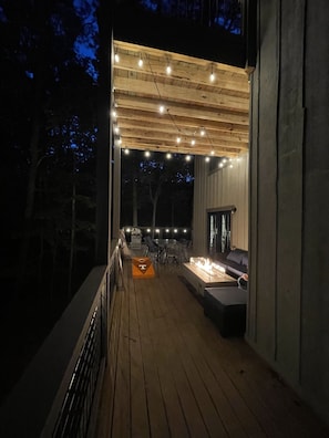 Terraza exterior con fogata, zona de estar y luces colgantes.