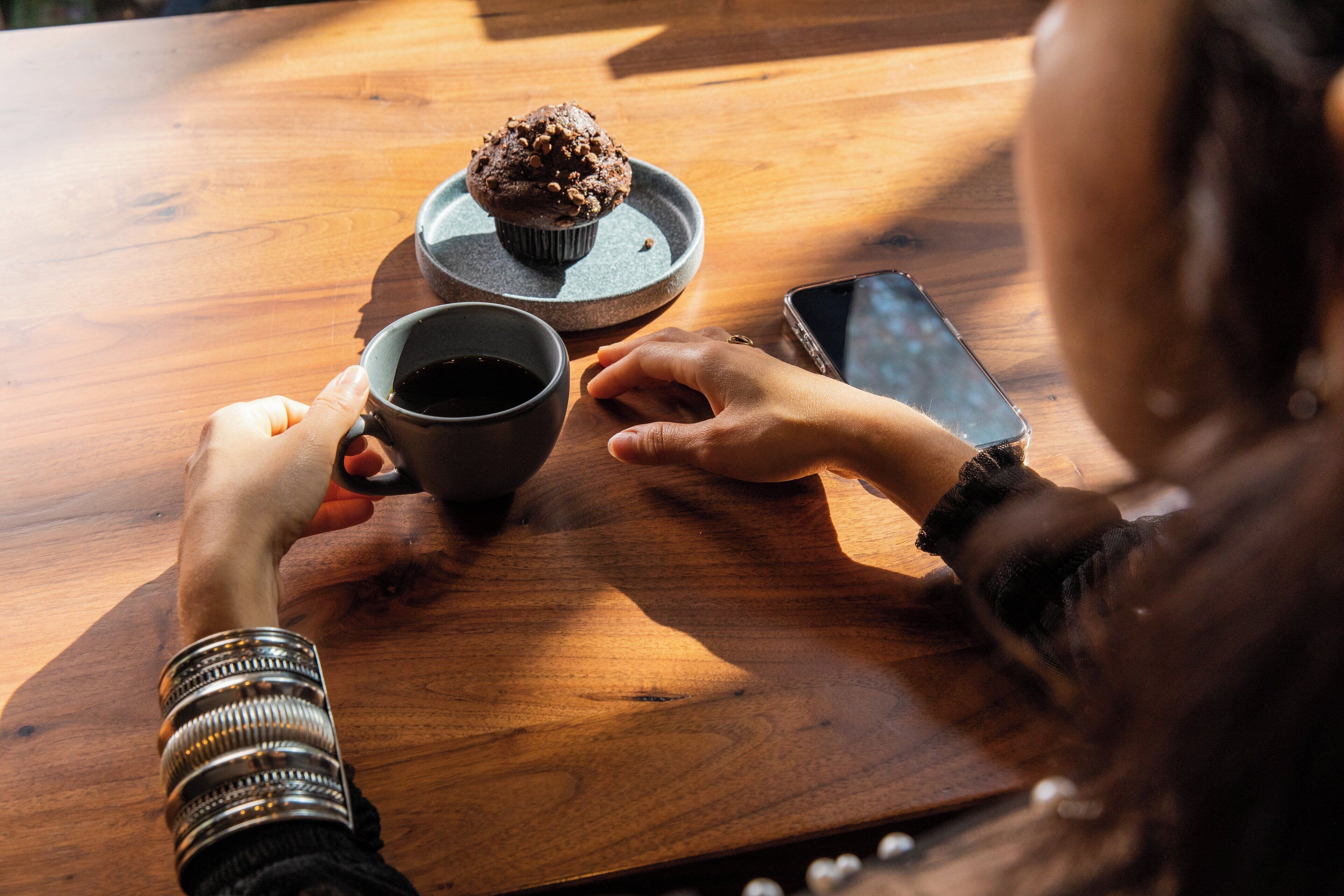 Une table en bois avec un muffin et une tasse.