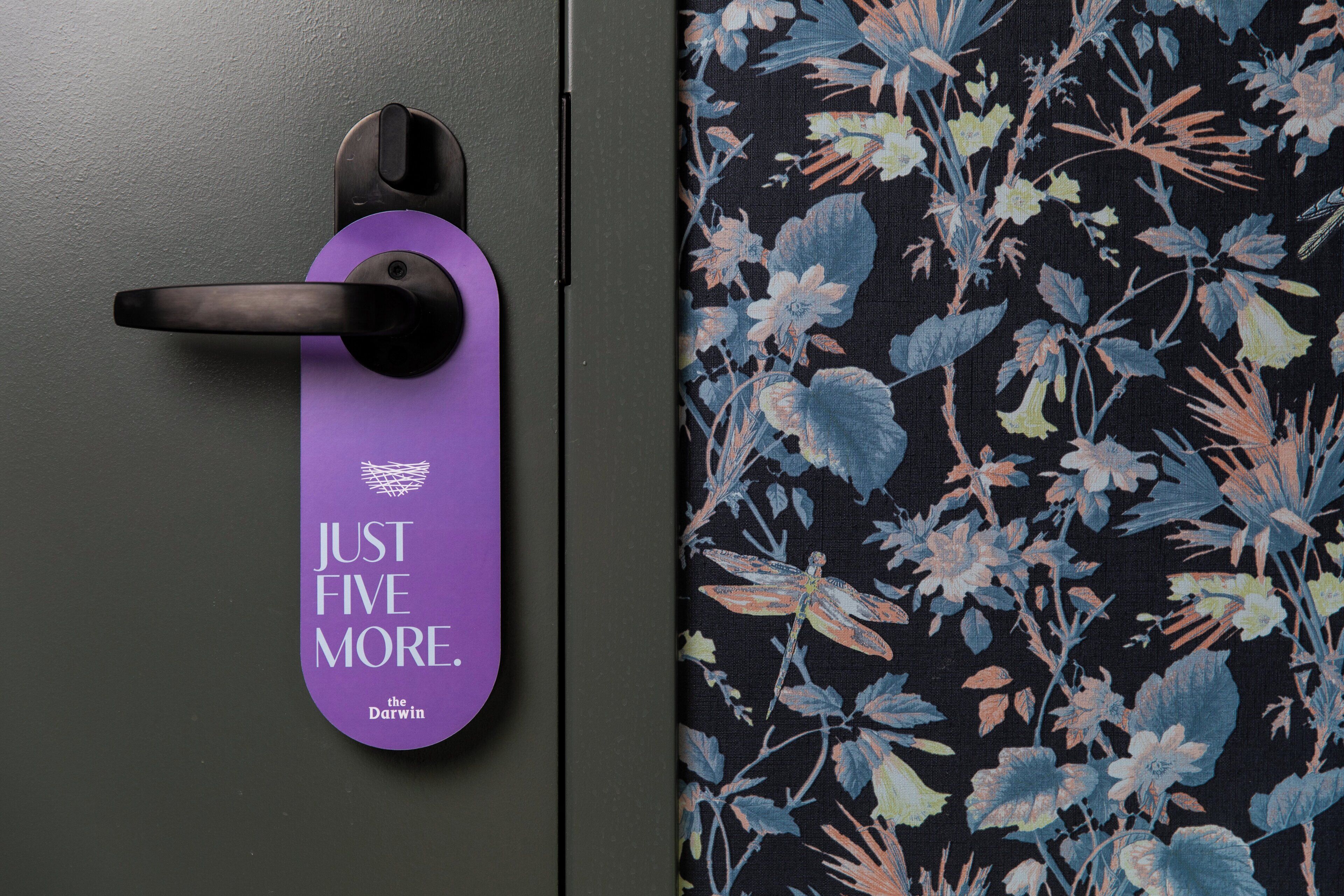 A door with a purple door hanger that reads "JUST FIVE MORE."