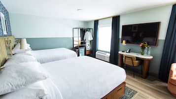 Quarto de hotel com duas camas, uma escrivaninha, uma cadeira, uma televisão e uma janela com cortinas.