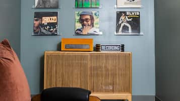 A room with a wall decorated with framed album covers, a wooden speaker, and a black chair.