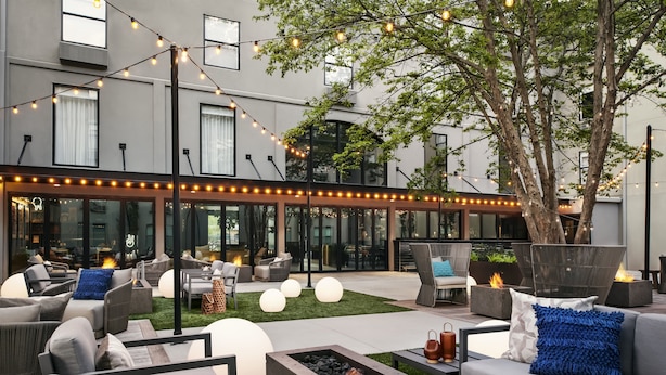 Een terras met moderne meubels, lichtjes en een vuurkorf.
