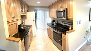 Una cocina con armarios de madera, un refrigerador de acero inoxidable, un microondas, una estufa y un lavavajillas.