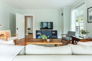 Een woonkamer met een bank, een salontafel, een televisie en een boekenkast.