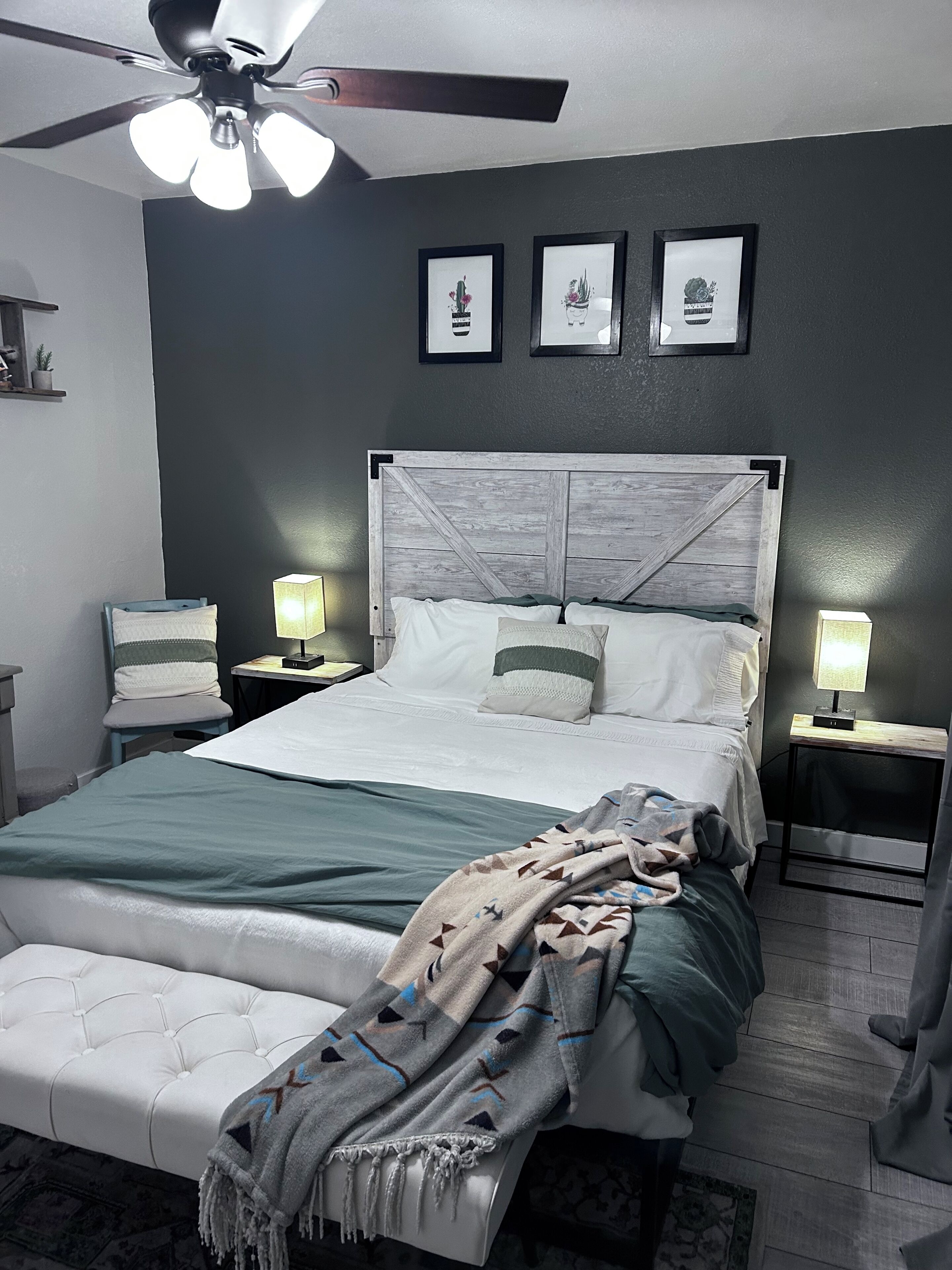 Una camera da letto con un letto, comodini, una ventola a soffitto e opere d'arte appese al muro.