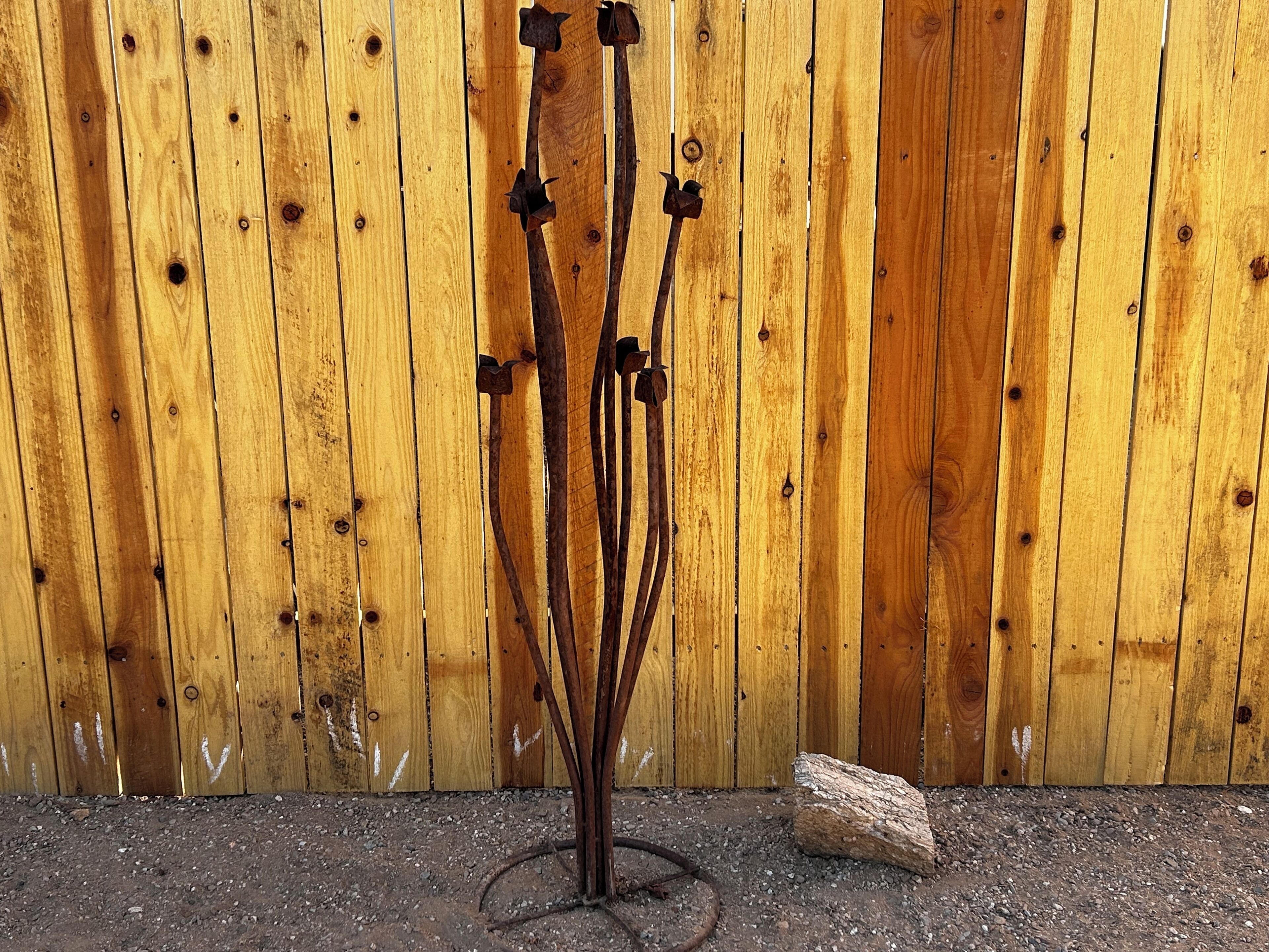 Una escultura de metal con múltiples ramas sobre un fondo de cerca de madera.