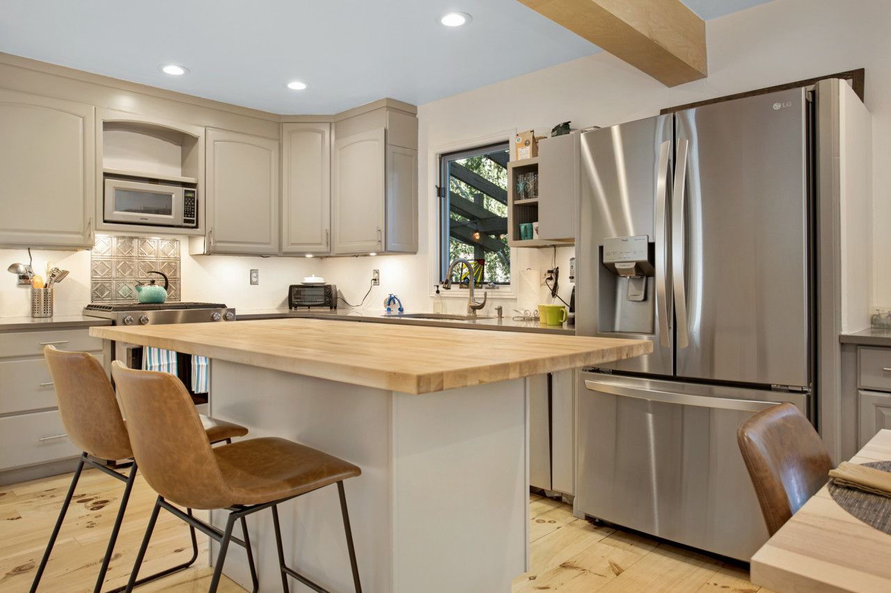 Une cuisine moderne dotée d’un îlot central, d’appareils électroménagers en acier inoxydable et de chaises en bois.