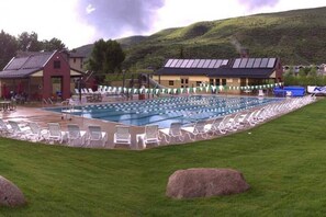 A swimming pool with lounge chairs and a building with a sloped roof.