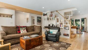 Una sala de estar con sofá, sillón, mesa de centro y estanterías.
