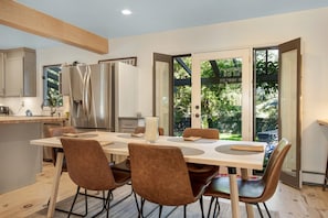 Cocina moderna con comedor, que incluye una isla grande, electrodomésticos de acero inoxidable y vistas a través de puertas de cristal.