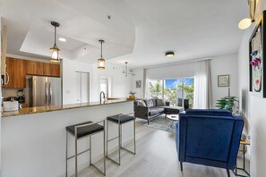 A modern kitchen with a refrigerator, bar stools, and pendant lighting. - Newly renovated 2/2 apt-2 min walk to the beach and restaurants (Deerfield Beach)