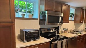 Une cuisine avec des meubles de rangement en bois, un four à micro-ondes encastré, un four grille-pain et une cuisinière.