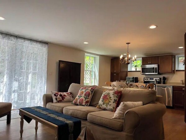 Relax in this inviting living space with a sofa, coffee table, and adjacent kitchen featuring a dining area and modern appliances.