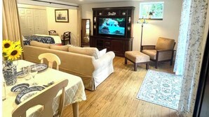 Un salon avec un canapé, un téléviseur, une table à manger et une fenêtre avec des rideaux.