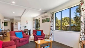 A living room with red sofas, a wooden coffee table, and a large window with curtains. - Great family holiday home with entertainment area for extras (Bowentown)