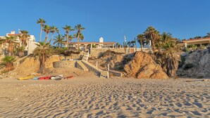 A beach with a staircase leading to a building, palm trees, and a rocky cliff. - Beachfront Villa + Casitas w/ pool. 6 BR (Los Barriles)