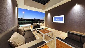 A modern living room with a pool view, a flat-screen TV, and a comfortable seating area.