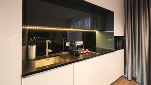 A modern kitchen with a large window, stainless steel appliances, and a sleek black countertop.