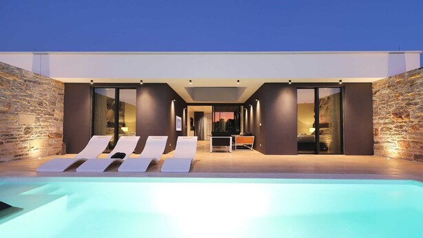 A modern outdoor pool area with lounge chairs and a dining table.